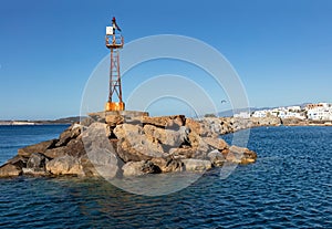 Beacon old rusty on rocky construction at Naoussa village harbor Paros island Cyclades Greece