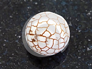Bead from cracked Cacholong gemstone on dark photo