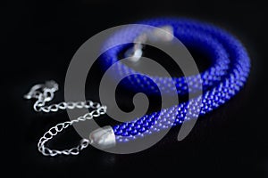 Bead crochet necklace blue color a dark surfce close up. Fashion background