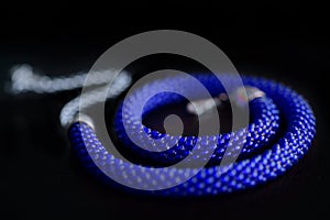 Bead crochet necklace blue color a dark surfce close up. Fashion background