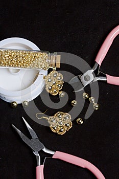 Bead jewelery. DIY jewelry. Necessary accessories. Beads and ready-made earrings. Tools and fixtures. On a black background.