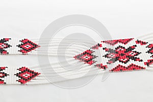 Beaded ethnic red and black necklace on white fabric background. Female accessories, decorative ornaments and jewelry.