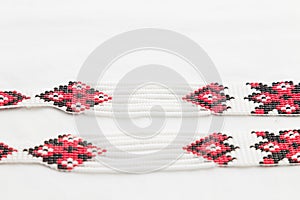 Beaded ethnic red and black necklace on white fabric background. Female accessories, decorative ornaments and jewelry.