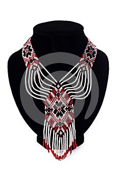 Beaded ethnic red necklace on black velvet bust isolated on white background. Female accessories, decorative ornaments and jewelry