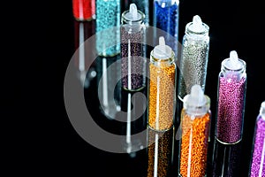 Beads in bottles for the design of nails diagonally on a black background