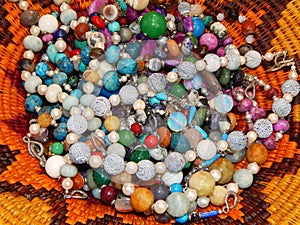 Beads and bracelets from semi-precious stones on a wicker plate.