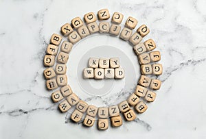 Beads with word KEYWORD on white marble background, flat lay