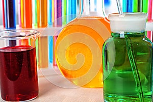 Beaker, flasks and test tubes with colorful liquids on table, closeup
