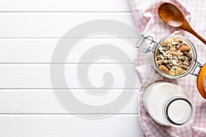 Beakfast cereals in bowl and milk in bottle. Healthy muesli with oat flakes, nuts and raisins