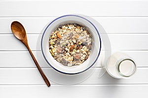 Beakfast cereals in bowl and milk in bottle. Healthy muesli with oat flakes, nuts and raisins
