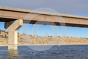 Beam bridge with abutment foundation against rugged land and cloudy sky