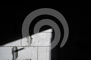 A beam of light illuminates a wall of aerated concrete bricks in the dark. Black and white photo of an unfinished renovation in a