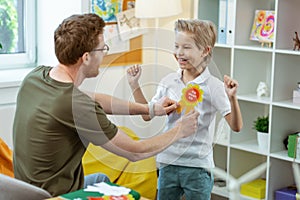 Beaming active kid in white t-shirt having bright rewarding sign