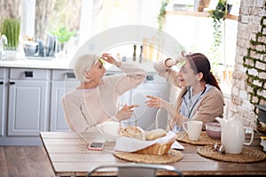 Beaming aged lady feeling happy spending time with caregiver