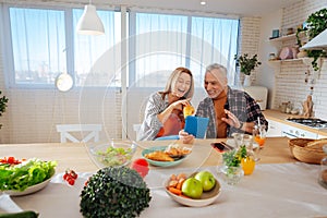 Beaming couple having much fun while enjoying breakfast