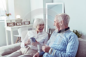 Beaming couple of pensioners feeling happy enjoying tea time together