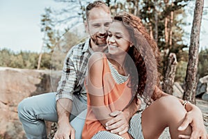 Beaming curly dark-haired woman feeling amazing near her handsome husband