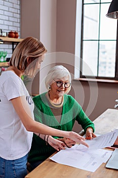 Beaming dame on pension considering loan application with granddaughter assistance