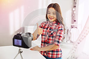 Beaming dark-eyed cute preschool girl filming her funny blog for followers