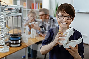 Beaming dark-haired boy in blue sweater carrying white 3d-model of head