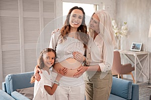 Beaming dark-haired expecting woman spending time with family