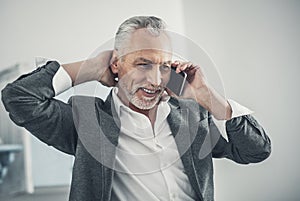 Beaming elderly man speaking by the phone