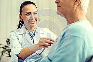 Beaming female doctor listening to heart beating