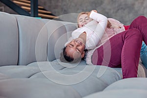 Beaming girl lying on her mother while spending day at home