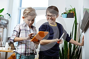 Beaming good-looking young boys carrying tablet and marker