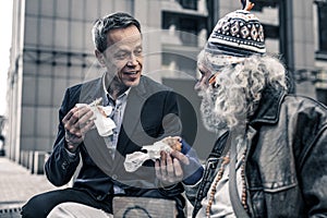 Communicative kind man talking to grey-haired senior homeless photo