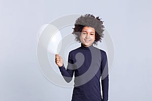 Beaming little boy standing on monochromic background and carrying