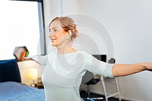 Beaming mature woman with tied hair having workout morning session