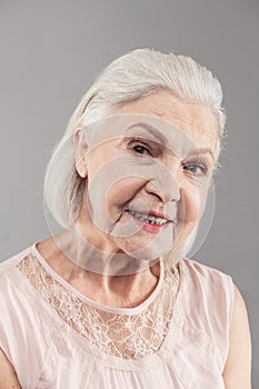 Beaming old woman with short hair working as model in studio