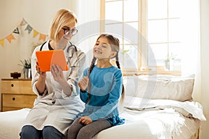 Beaming pediatrician laughing and having fun with a small girl.