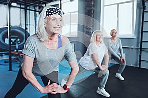 Beaming senior lady taking group training at gym