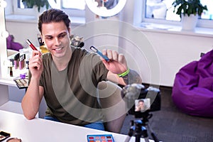 Beaming short-haired young man creating makeup video