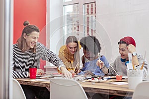 Beaming students of art department laughing painting together