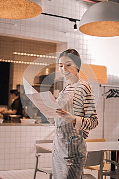 Beaming successful woman looking at menu of her little cafeteria