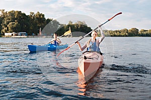 Beaming woman wearing life vest holding paddles while kayaking