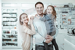 A beamingly smiling family sharing cuddles near the pharmacy checkout photo