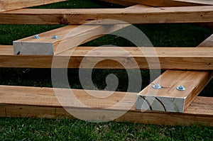 Beams connected by screws in the shape of v. future roof of the pergola fixed to the ground by means of metal foundation profiles