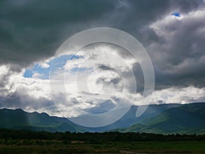 Beams of sunlight shining through dark rainy clouds  after rain down on the earth