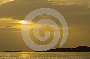 Beams of yellow light with refletions on a water surface before sunset, Sithonia