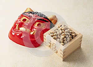 Beans for bean-throwing and masks of ogres placed on a Japanese-style golden background. Japanese ogres