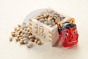 Beans for bean-throwing and masks of ogres placed on a Japanese-style golden background. Japanese ogres