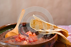 Beans cooked in a clay dish with tomato and tortillas, mexican poor dish