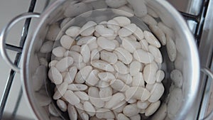 Beans in a pot of water on a gas stove top view.