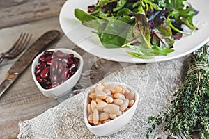 Beans are white and red with large black olives in white small cups with green leaves of arugula and Lollo Ross prepared photo