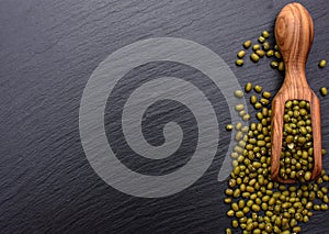 Beans wooden scoop on the background of a black stone board, place for text, mung bean