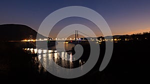 Bear Mountain bridge lit up at night over the river